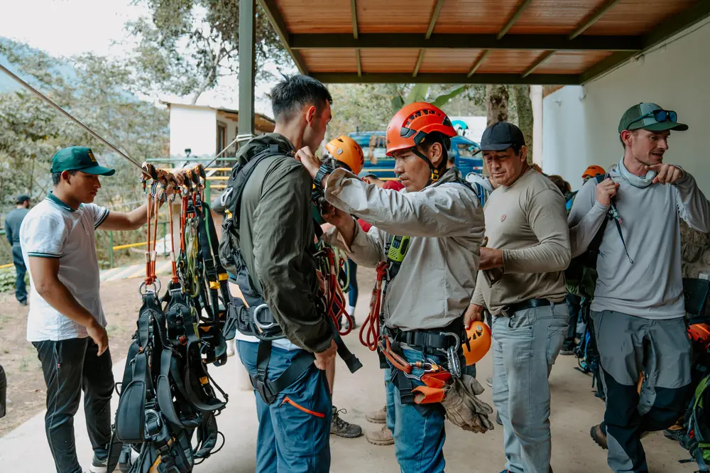 A guide fitting a safety harness on a visitor before the zipline circuit