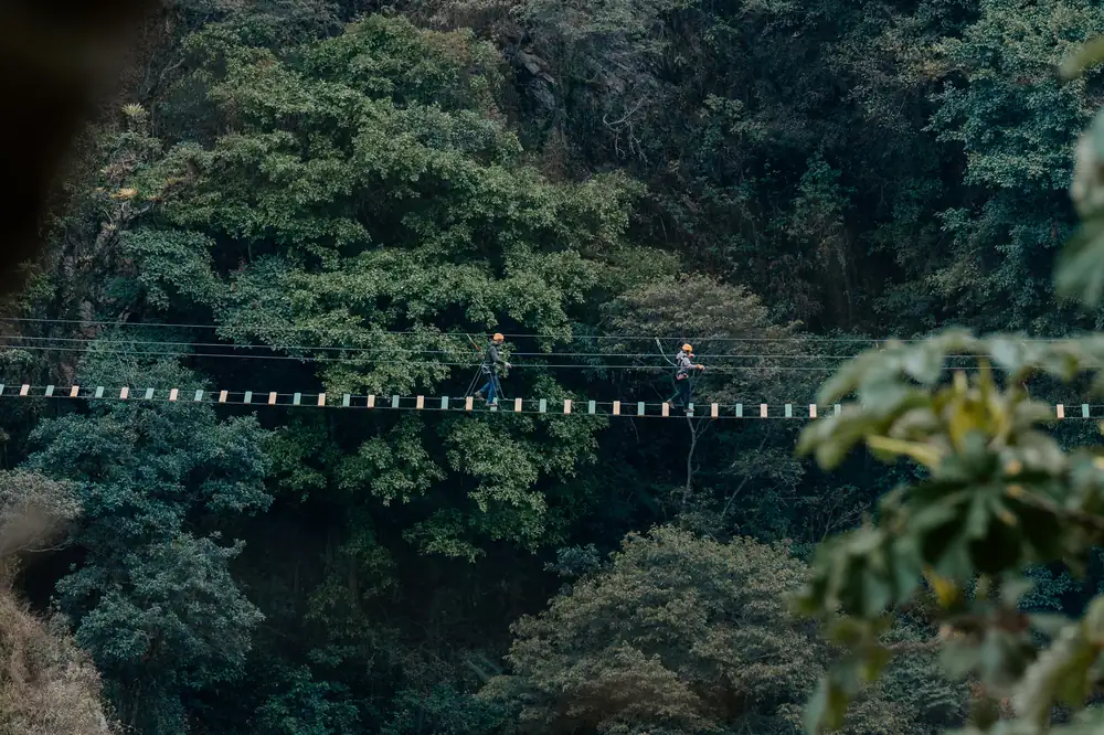 Two people crossing the 300 metre Tibetan suspension bridge high above the Salkantay valley